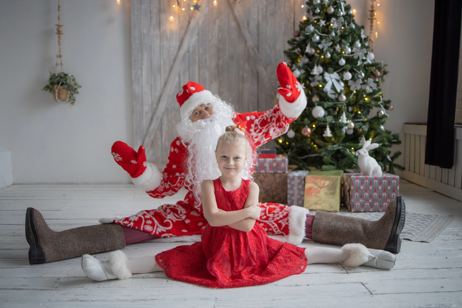 Child in Santa Claus suit around Christmas tree